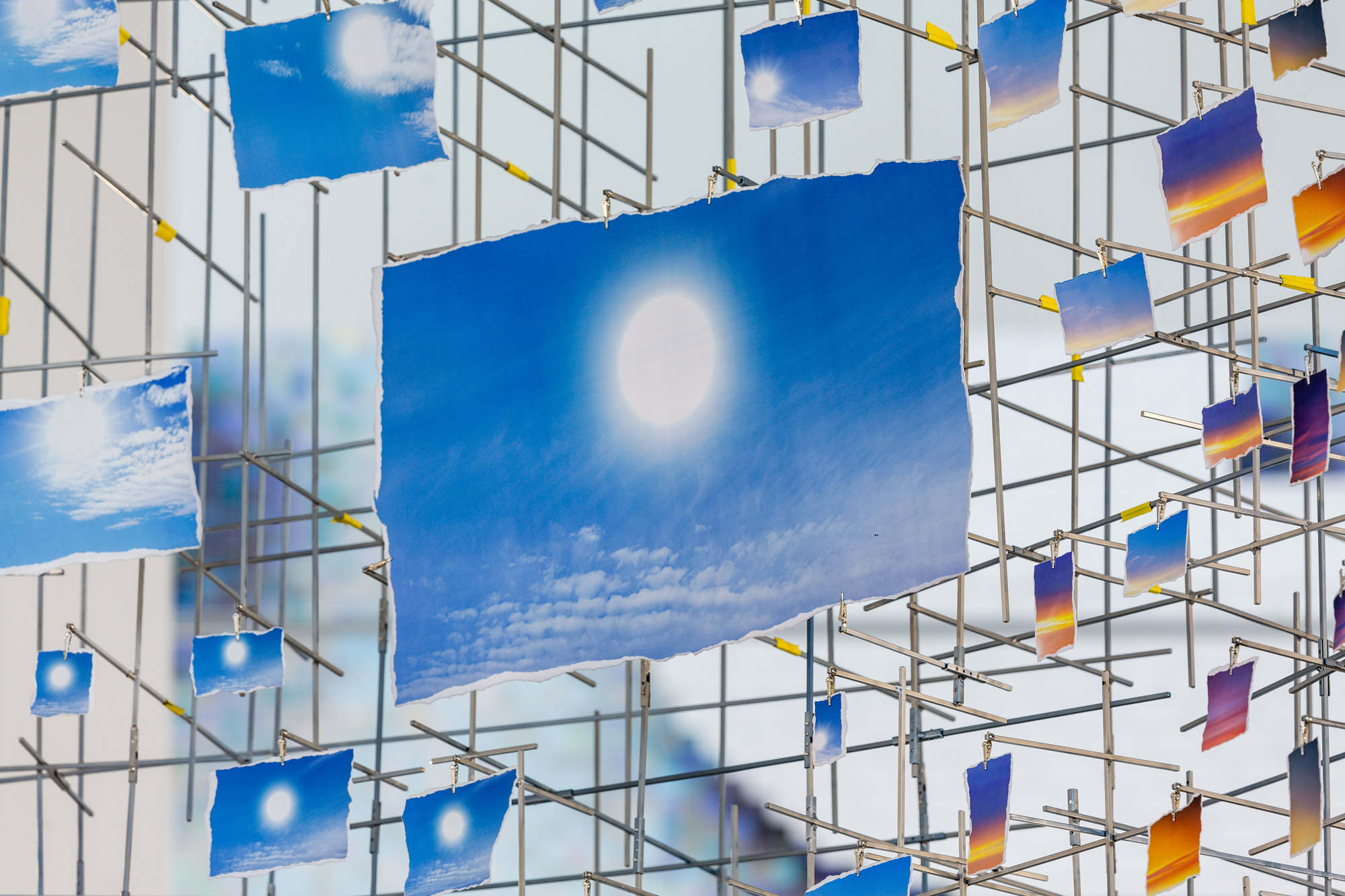 A closeup view of a constellation of snapshots of the sky above New York City, which form a mirage-like sphere that appears to float in midair.