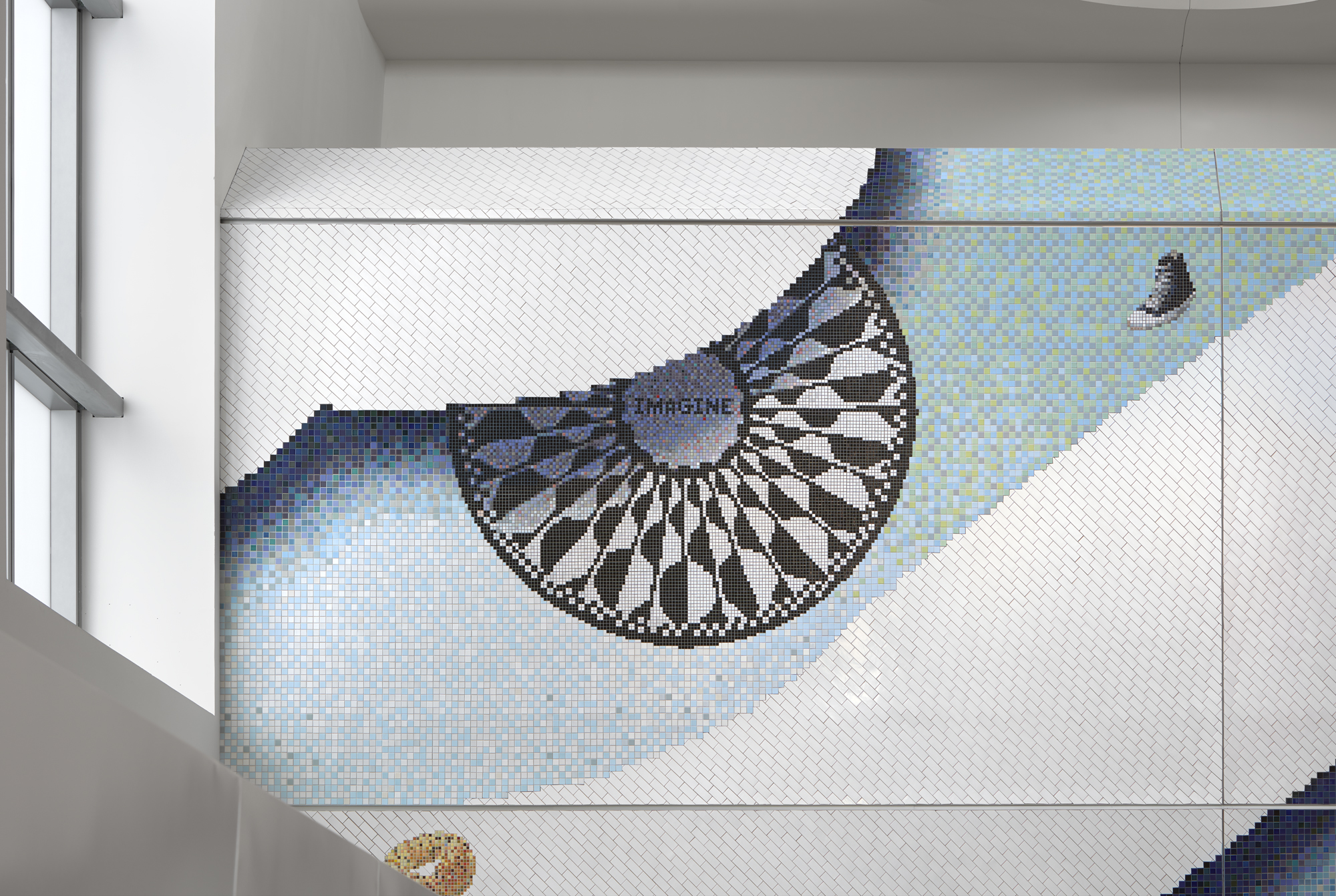 A tiled mosaic of the imagine john lennon mosaicfloating against a light blue background with the edge of a large cloud on the top left.