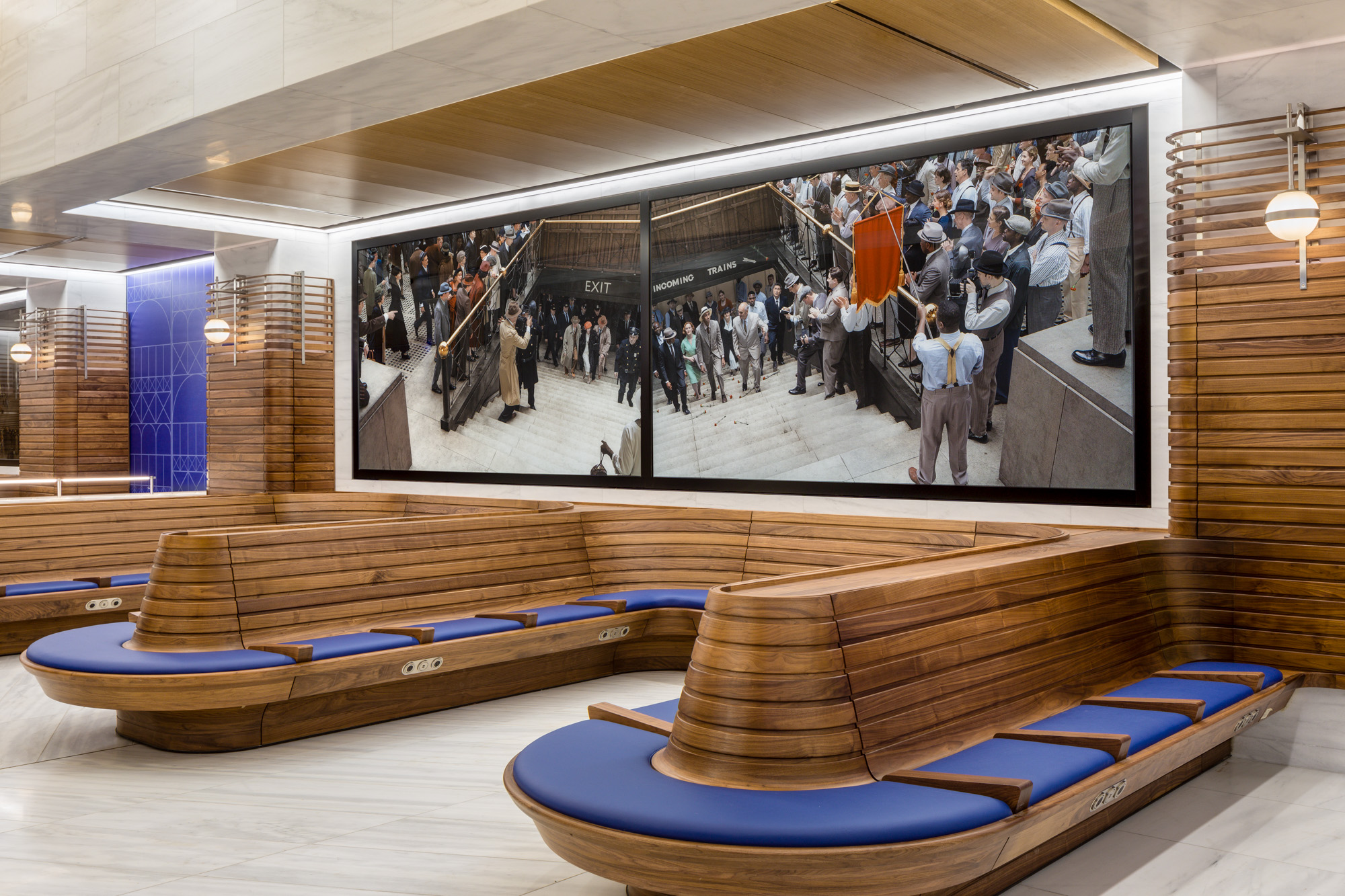 Two horizontal panels of photographs, with blue upholstery and wood seating below the panels. The two photographs depict reenactments of significant but little-known...