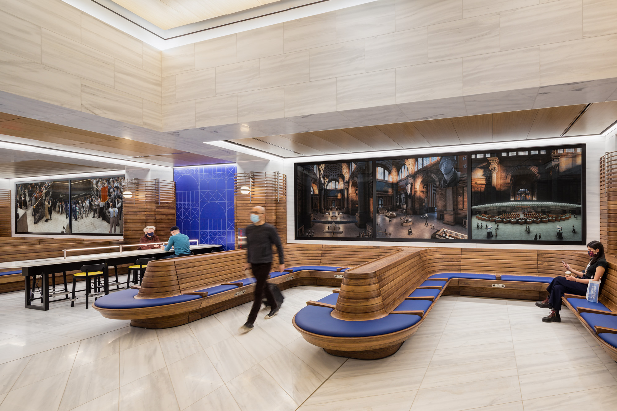 Two horizontal panels of photographs, with blue upholstery and wood seating below the panels. The two photographs depict reenactments of significant but little-known...