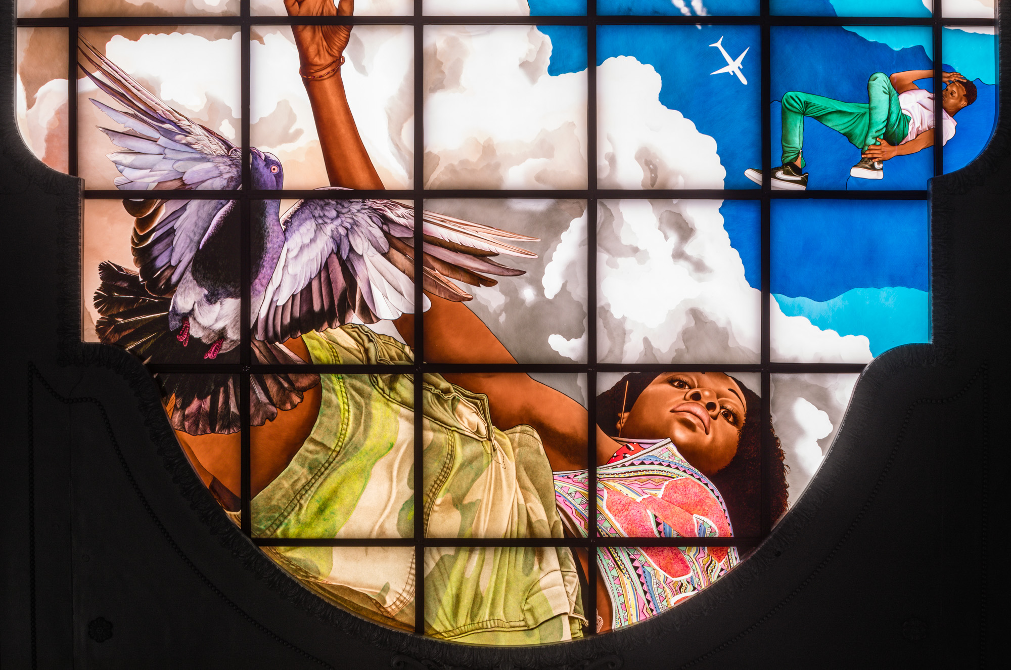 detail of a brightly painted stained glass triptych depicting ya young Black woman in a pose drawn from breakdance, set against billowing clouds in a brilliant...