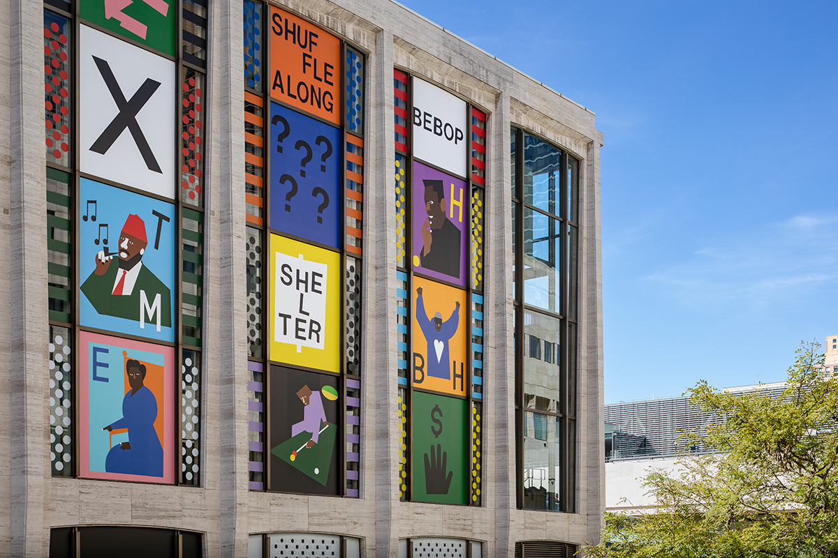 A close-up of the facade of a music hall building with a composition of colorful, graphic portraits...