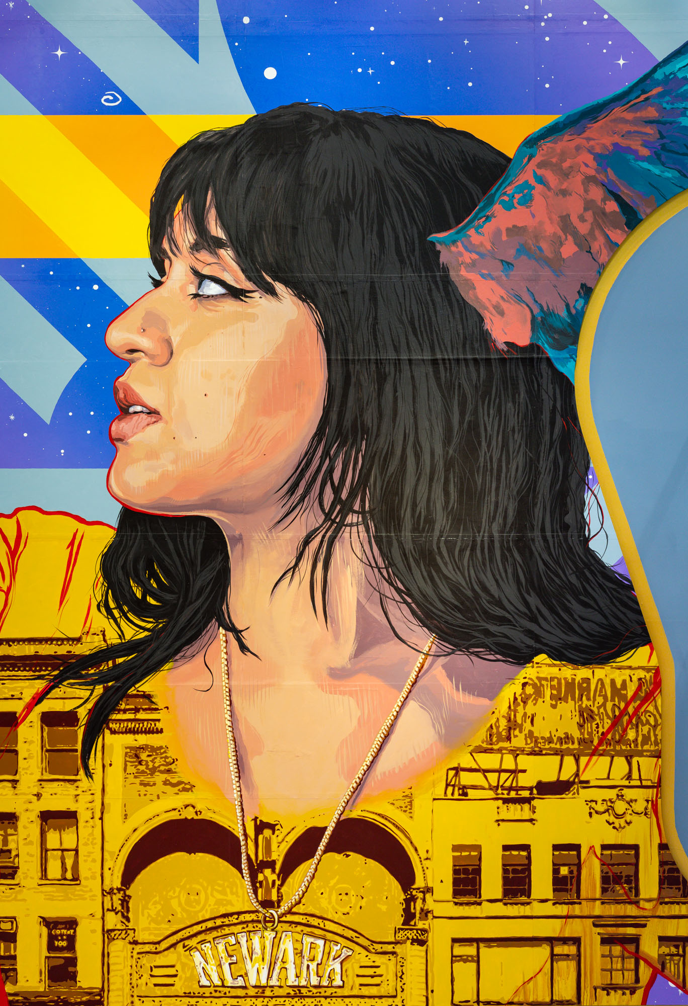 Close-up of painted mural depicting a woman with straight dark brown hair looking up, with pink and teal wings sprouting from her head and a Newark building superimposed...