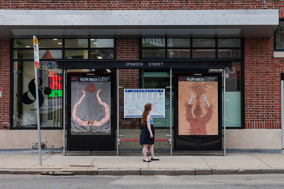 Pictured on a bus shelter on a busy city street are two layered hybrid figure that merges human, artifact, animal, and vegetation. One work is tan with a figure...