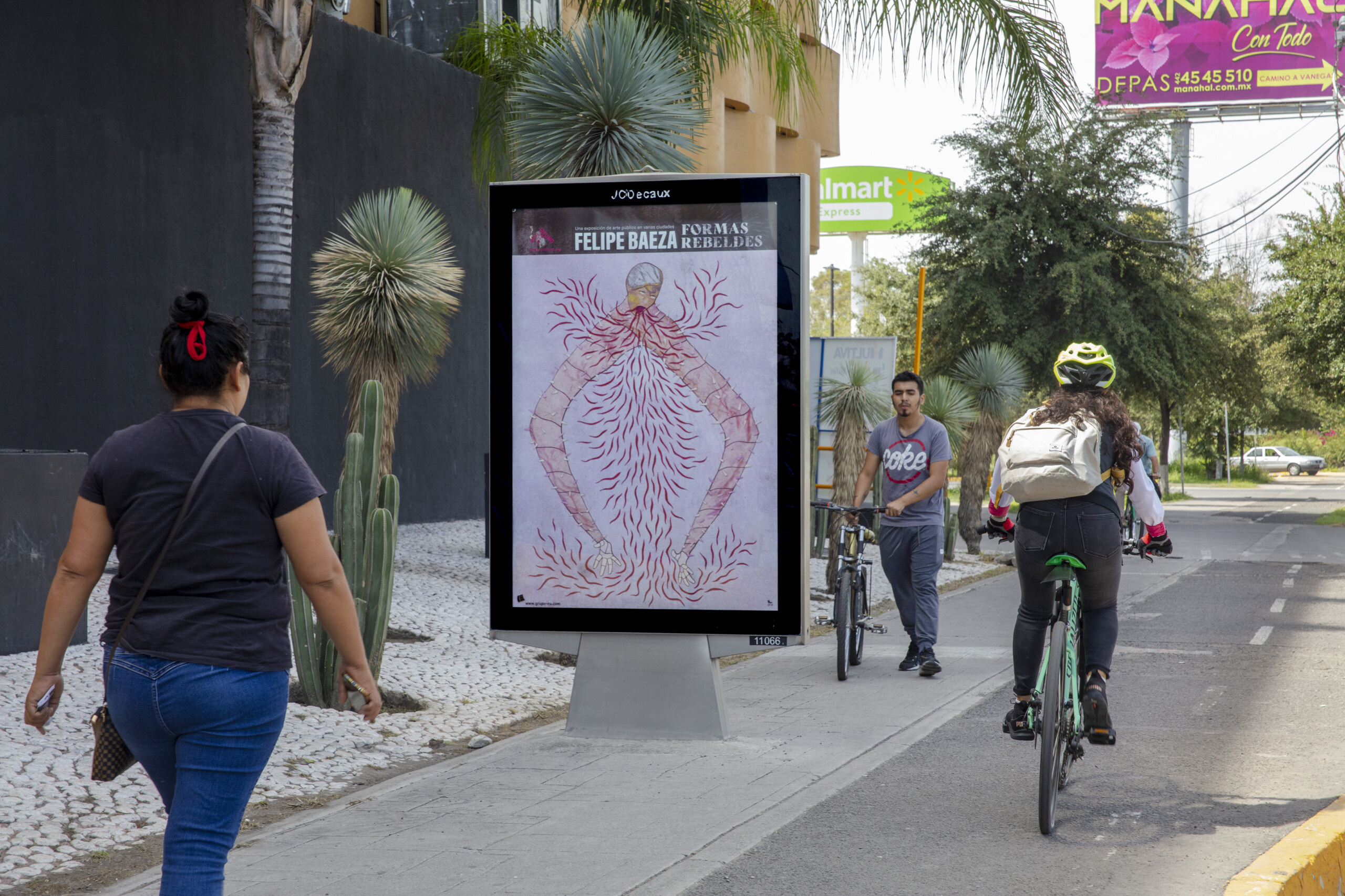 Pictured on a bus shelter on a busy city street is a layered hybrid figure that merges human, artifact, animal, and vegetation.