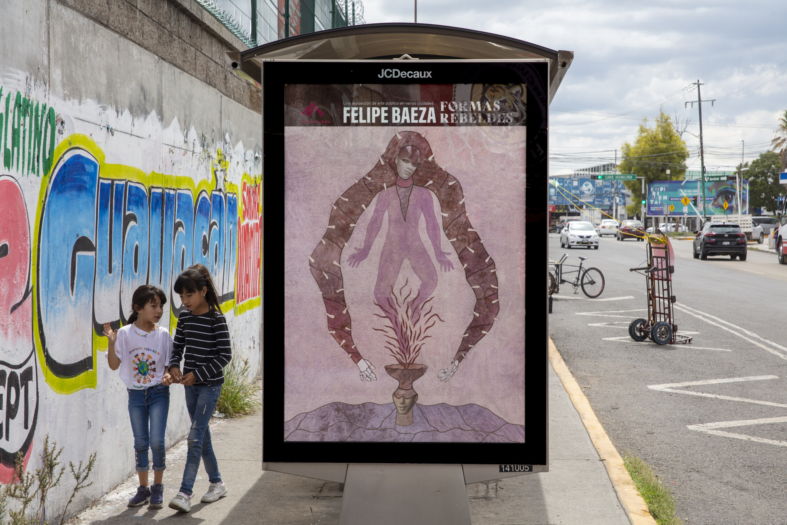 Pictured on a bus shelter on a busy city street is a layered hybrid figure that merges human, artifact, animal, and vegetation.