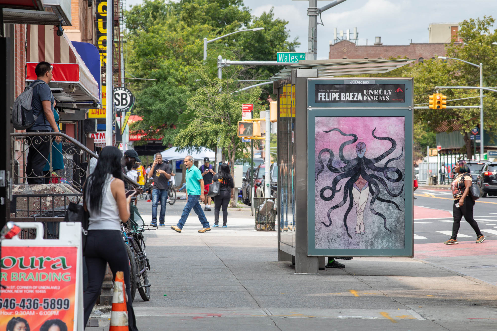 Pictured on a bus shelter on a busy city street is a layered hybrid figure that merges human, artifact, animal, and vegetation.