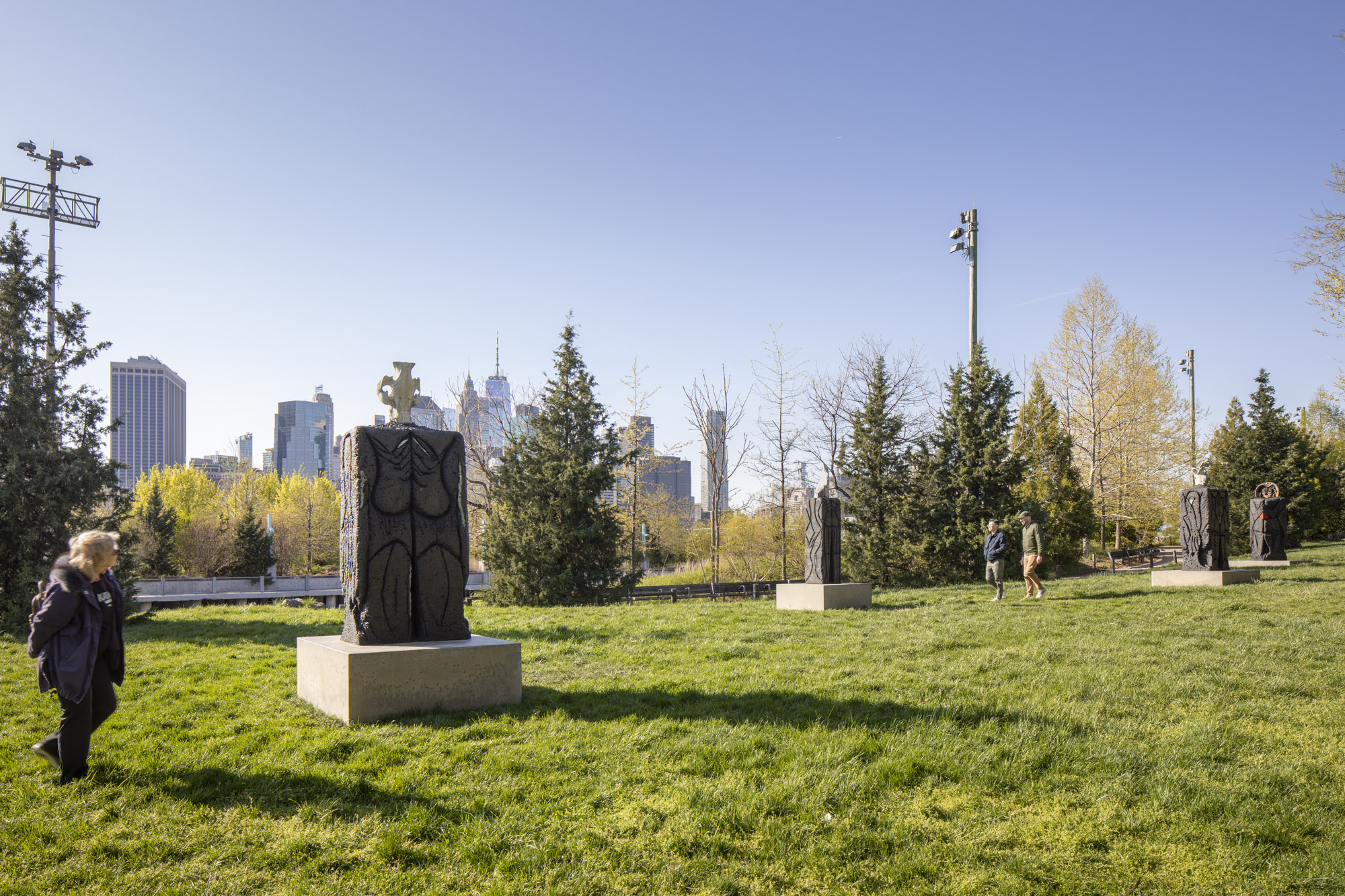 Four patinated bronze sculptures, each with a square concrete base, installed along a grassy terrace. On top of each sculpture sits a recreated skeletal structure:...